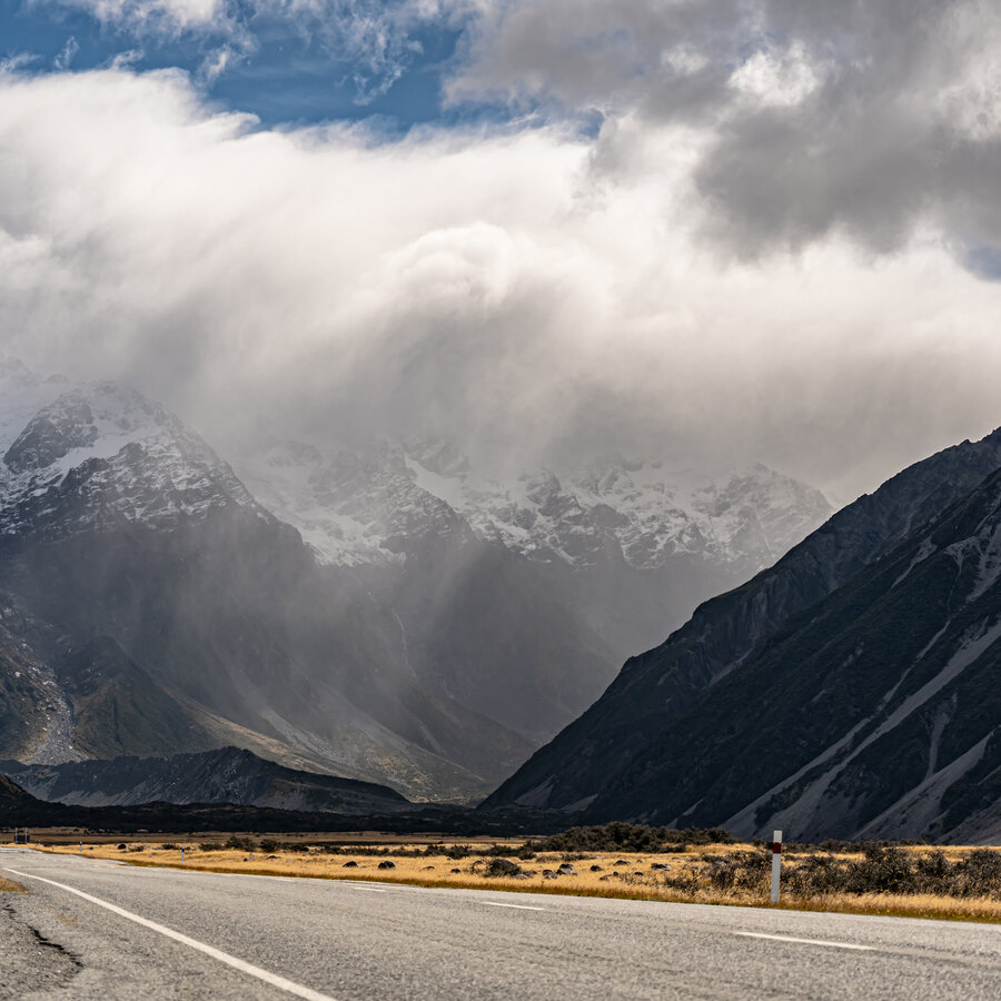 Clouds parting above a road and mountain valley in New Zealand