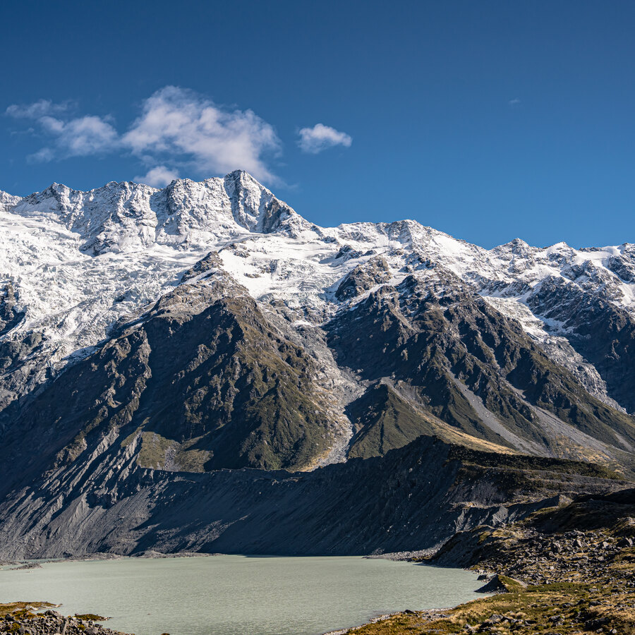 Snow-covered peaks above a glacial lake under a clear blue sky