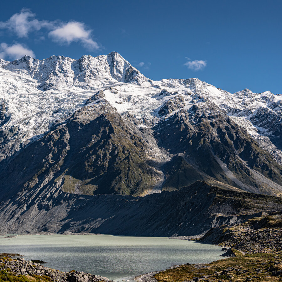 A snow-covered mountain range reflected beside a pale alpine lake