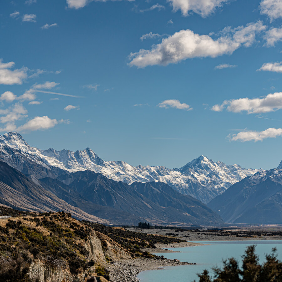 A turquoise lake beneath a wide mountain range and scattered clouds