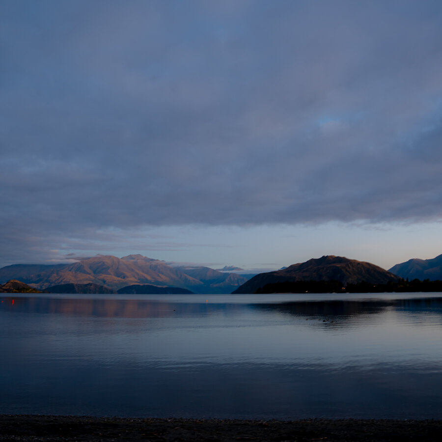 A dark blue lake and distant ridges beneath evening cloud